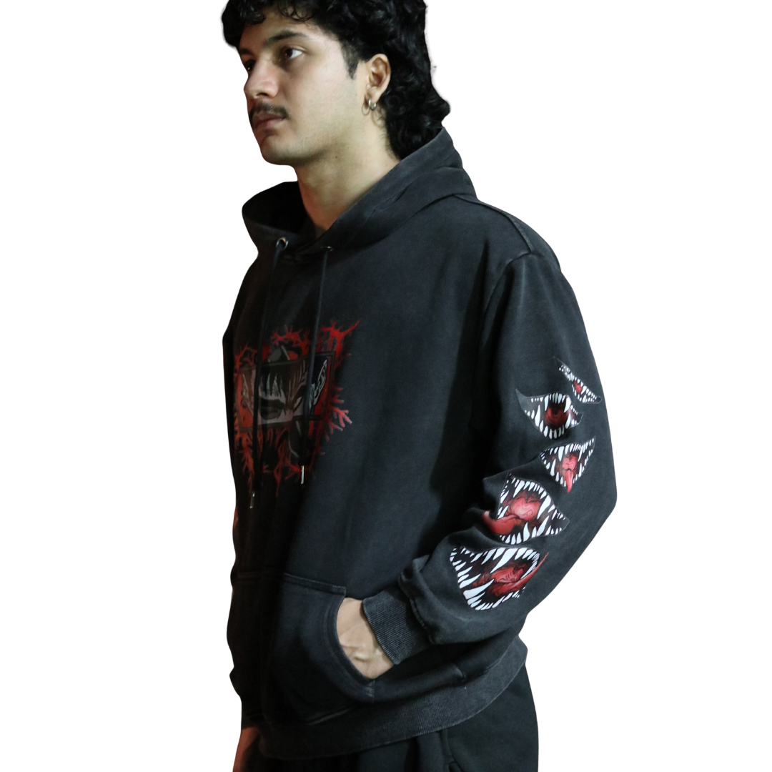 Person wearing a black hoodie with graphic designs on sleeves against a white background