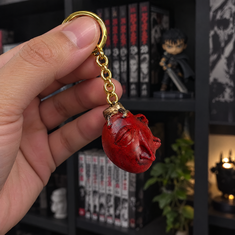Behelit keychain held up in front of a manga shelf